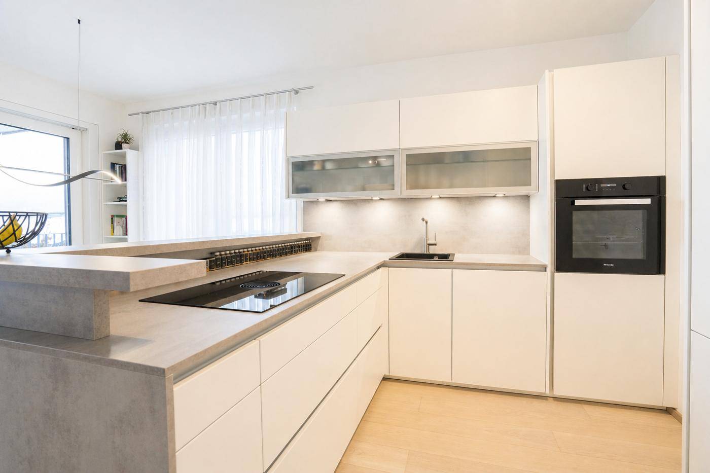 Hochwertige moderne Küche mit Induktionskochfeld, integriertem Backofen und viel Arbeitsfläche.