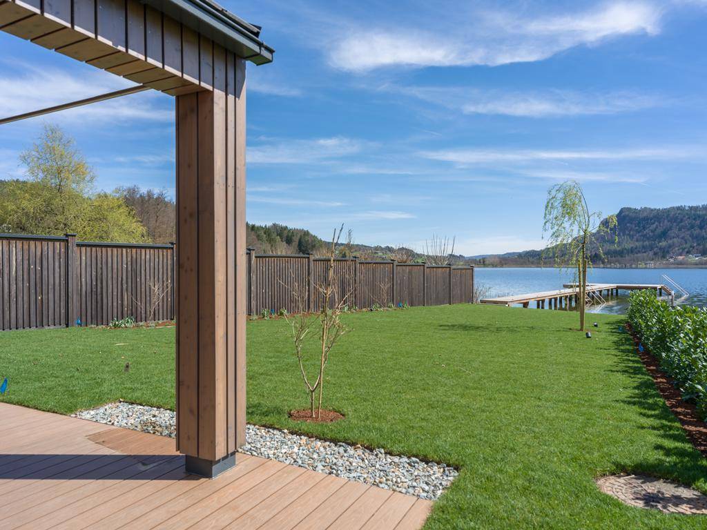 Gepflegter Gartenbereich mit Holzterrasse und direktem Zugang zum Seeufer mit Steg.