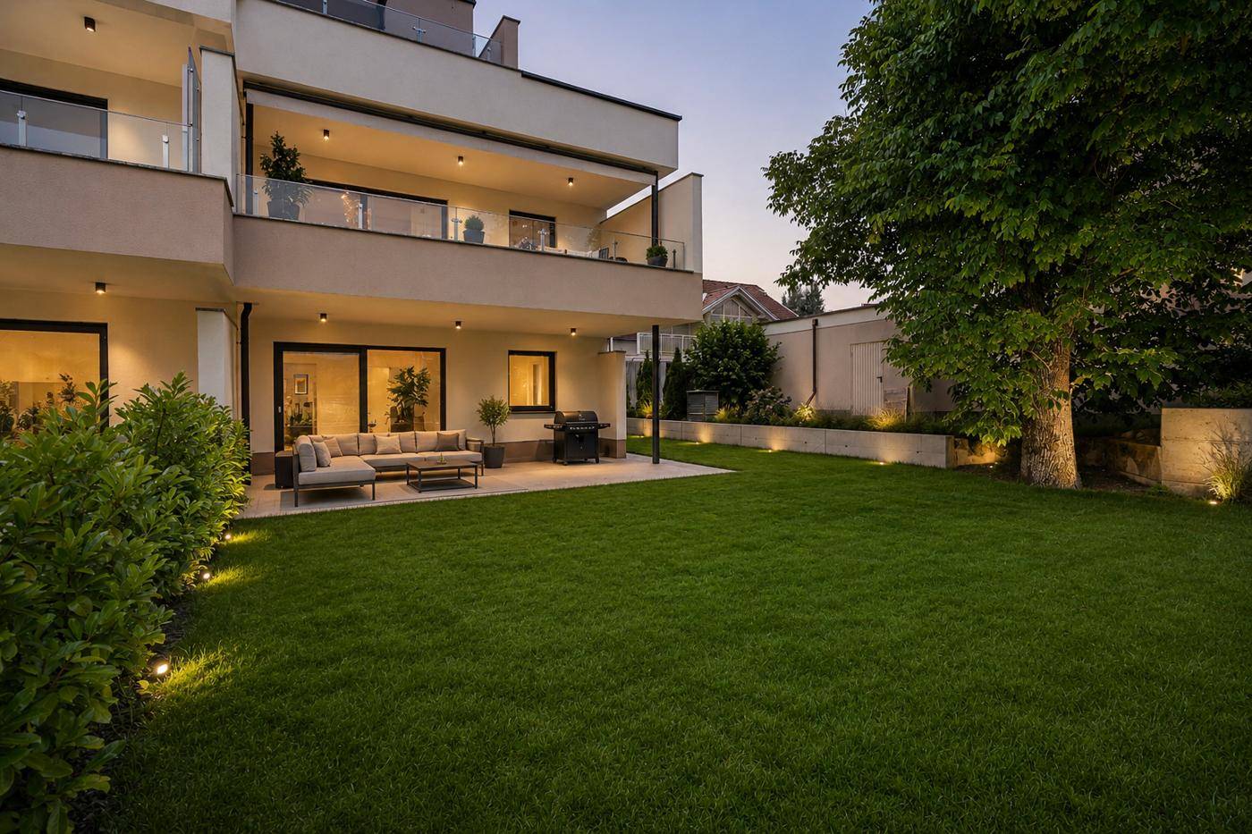 Gepflegter Gartenbereich mit großer Terrasse, bequemen Outdoor-Möbeln und stimmungsvoller Beleuchtung.