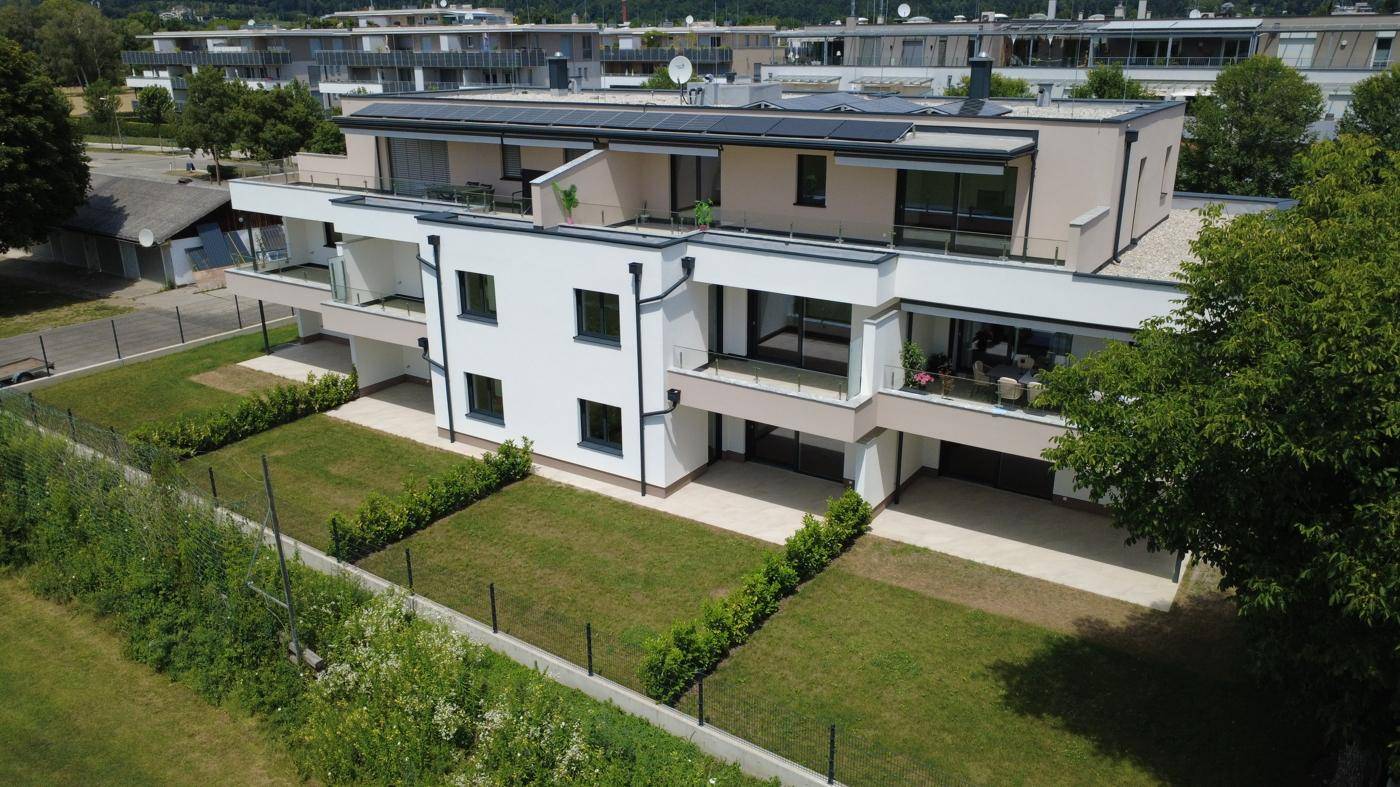 Luftaufnahme einer modernen Wohnanlage mit Flachdach, Balkonen und Photovoltaikanlage auf dem Dach.