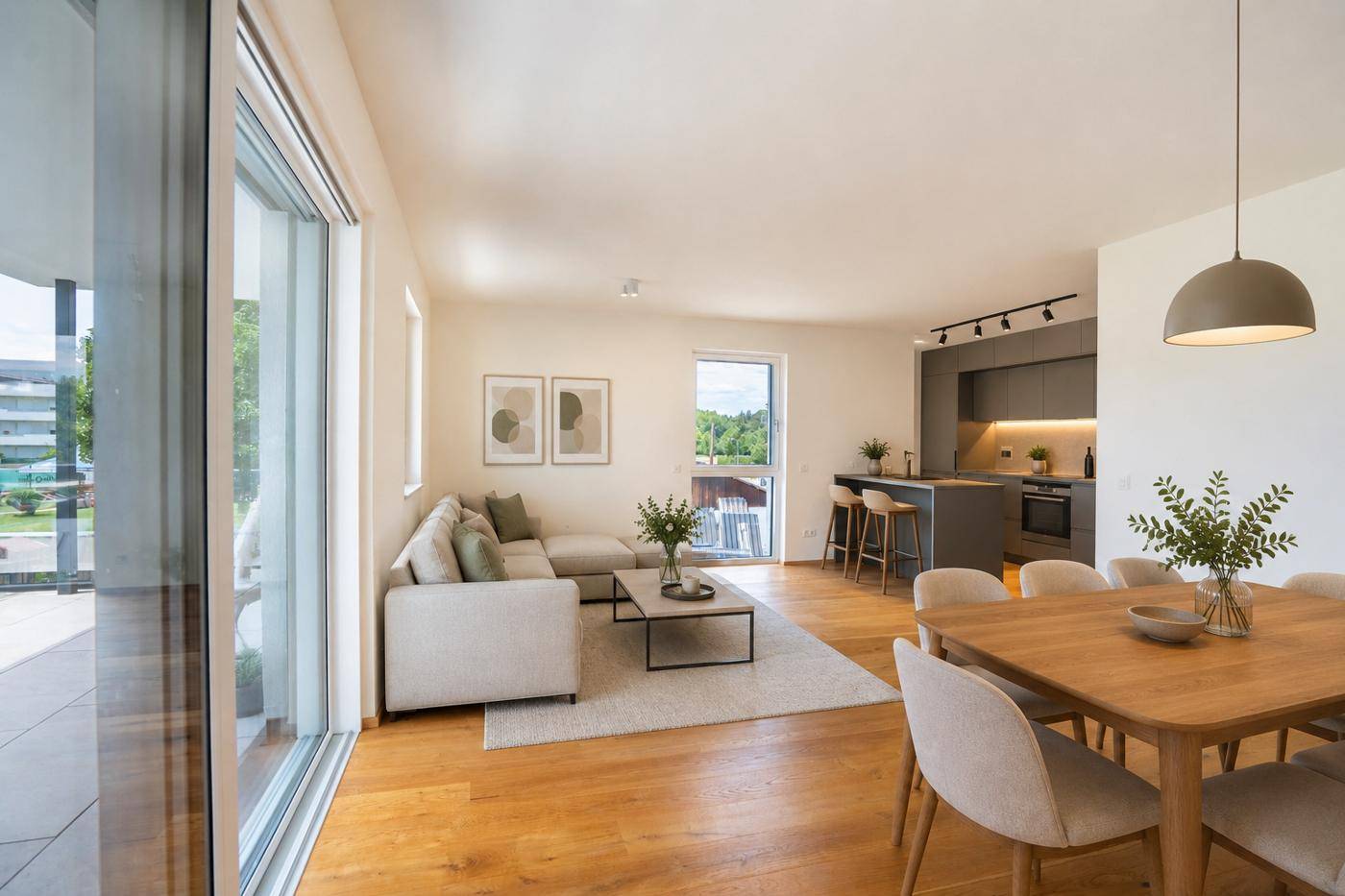 Heller offener Wohn-Essbereich mit moderner Küche, Holzboden und Zugang zur Terrasse.