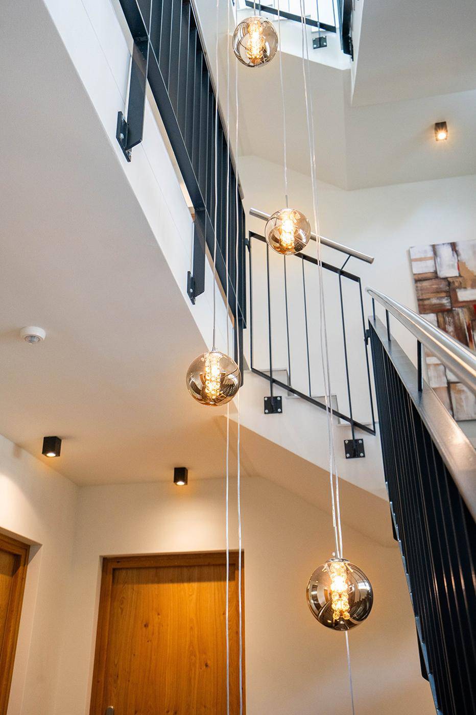 Modernes Treppenhaus mit eleganten Hängelampen und minimalistischem Design.