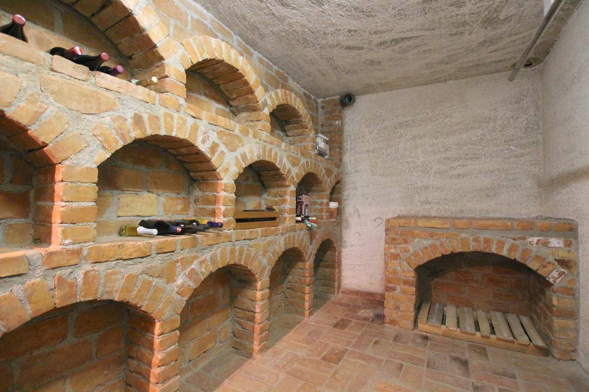 Rustikaler Weinkeller mit Ziegelgewölben und traditionellen Weinregalen.