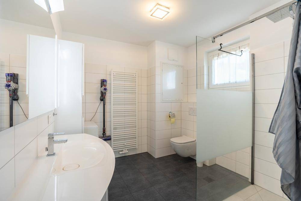 Modernes Badezimmer mit ebenerdiger Dusche, Waschtisch und beheiztem Handtuchhalter.