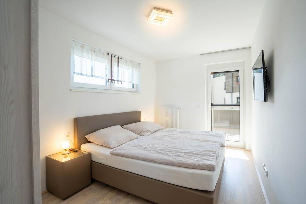 Schlafzimmer mit Doppelbett, Nachttischen und direktem Zugang zu einem Außenbereich.