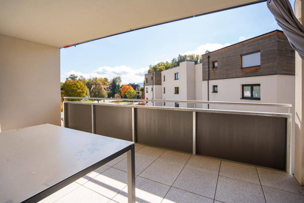 Geräumiger Balkon mit Fliesenboden und einem Tisch, ideal für entspannte Stunden im Freien.