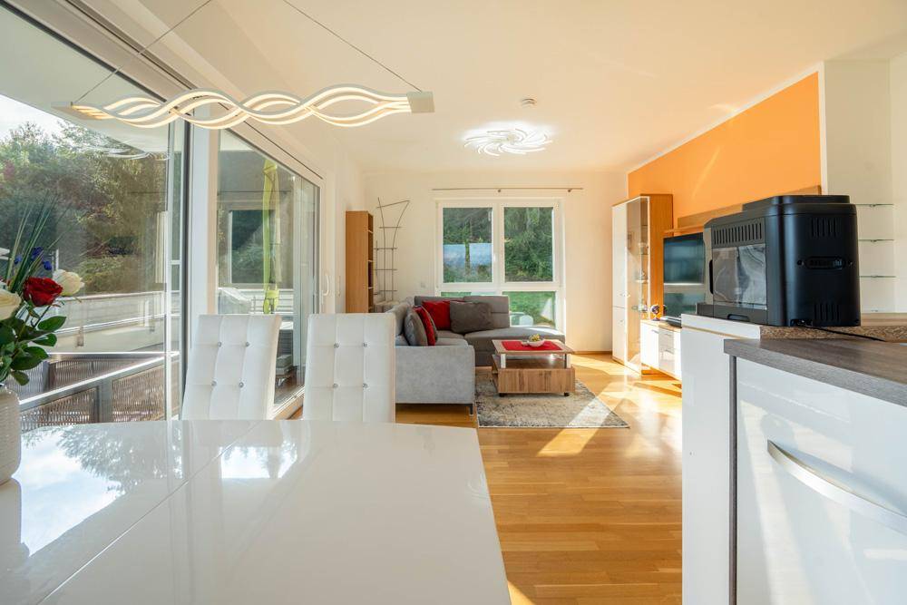Lichtdurchfluteter Wohnbereich mit modernem Sofa, Holzboden und großen Fenstern zum Balkon.
