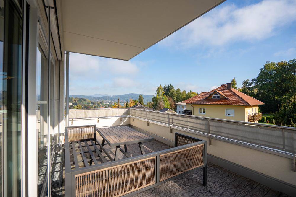 Geräumiger Balkon mit Holztisch und Stühlen, bietet einen Blick auf die Umgebung.