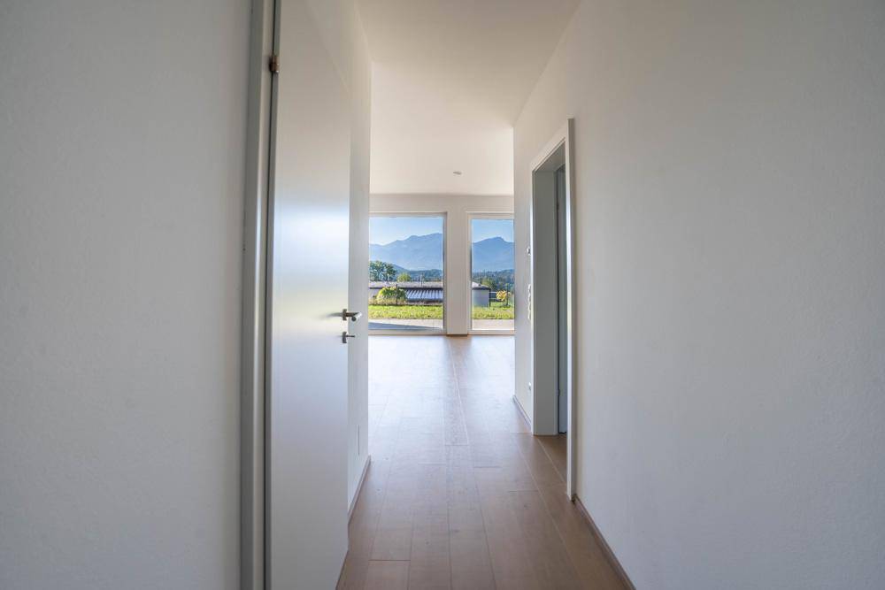 Heller Flur mit Holzboden, der zu einem Raum mit Panoramablick auf die Berge führt.