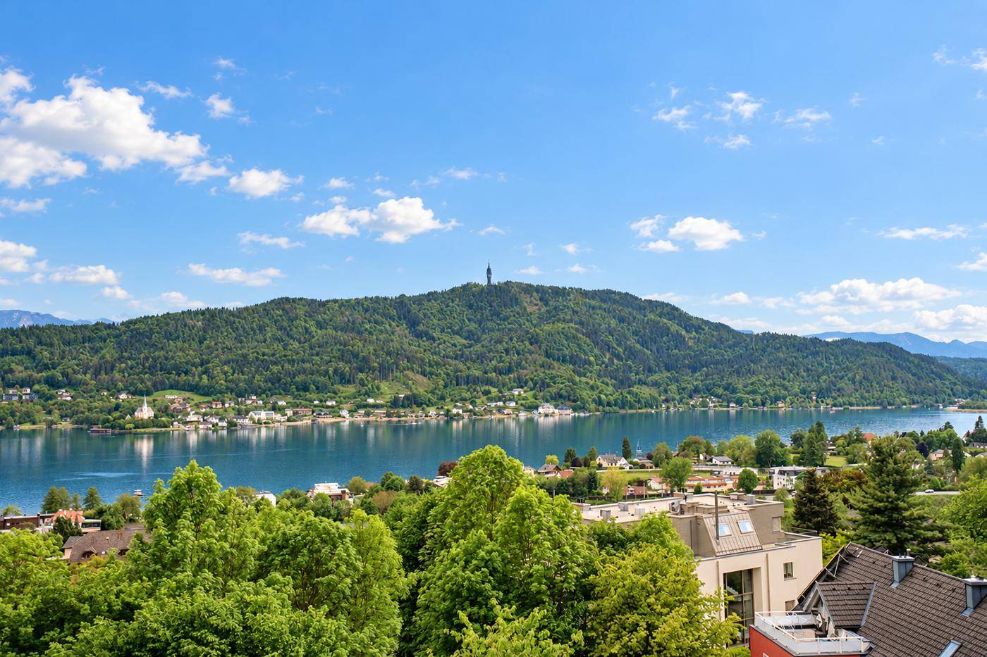 Malerischer Panoramablick auf den Wörthersee, die umliegenden Berge und die grüne Landschaft.