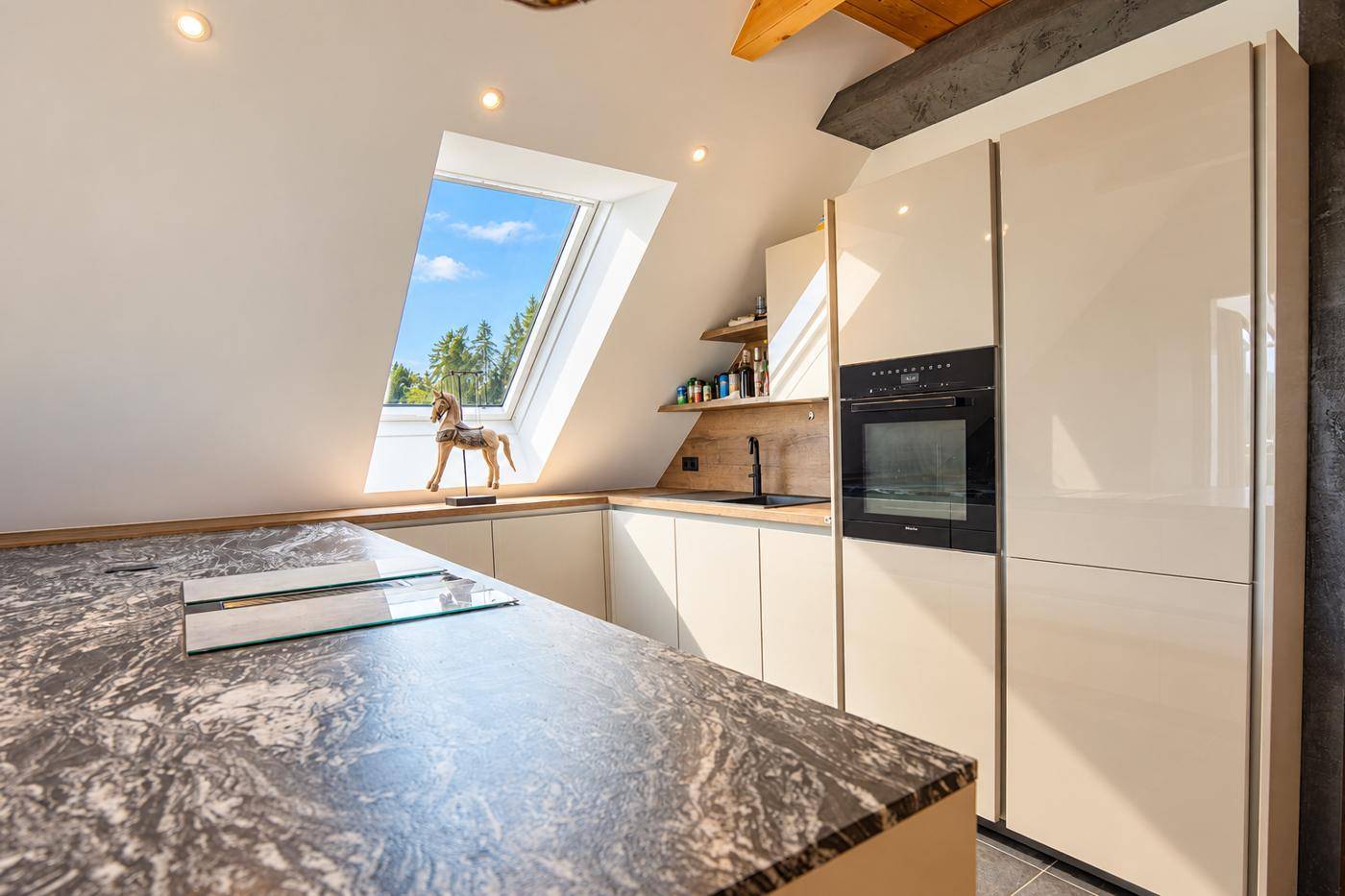 Hochwertige Küche mit Granit-Arbeitsplatte, integriertem Backofen und Dachfenster für viel Tageslicht.