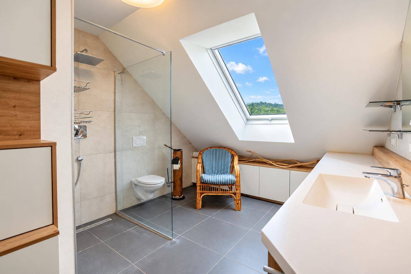 Modernes Badezimmer mit begehbarer Dusche, Waschtisch und großem Dachfenster unter der Dachschräge.