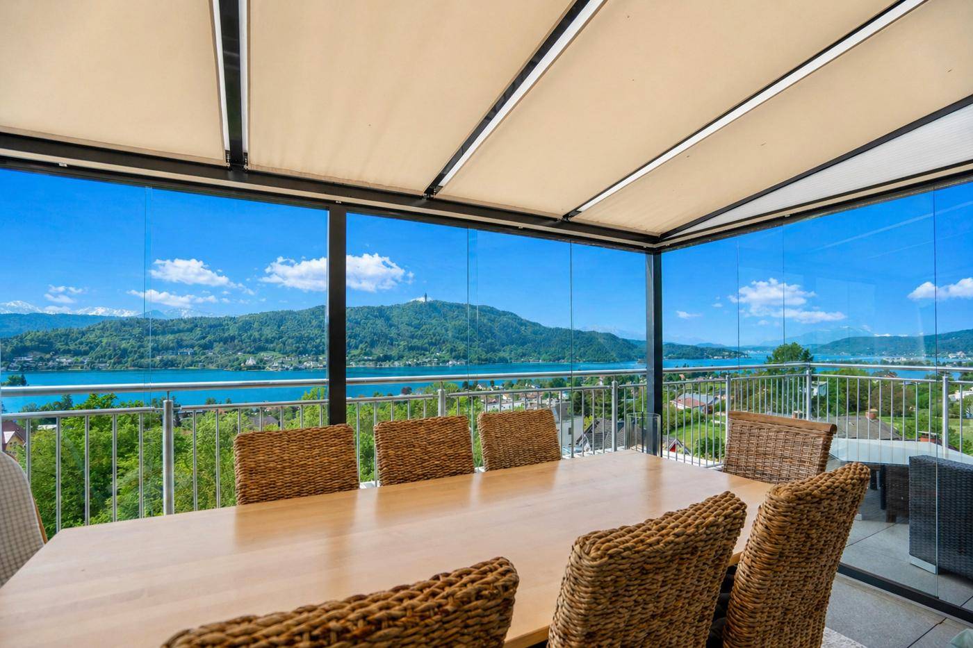 Überdachter Essbereich auf der Terrasse mit Rattanmöbeln und unvergleichlichem Panoramablick auf den See.