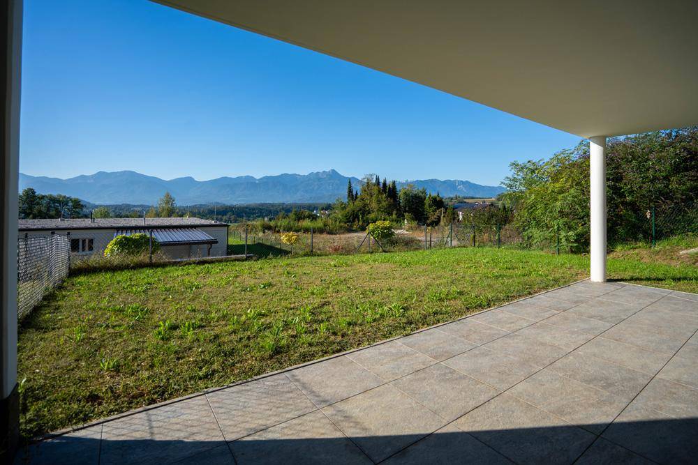 Geräumige Terrasse mit Blick auf die grüne Landschaft und die majestätischen Berge.