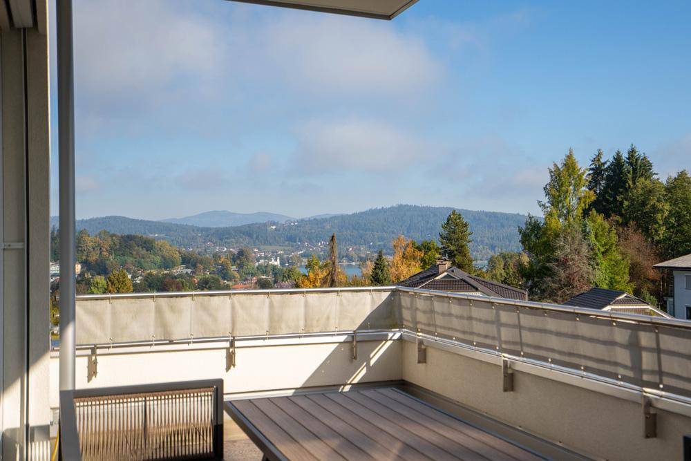 Geräumiger Balkon mit Holzboden und atemberaubendem Blick auf die umliegende Landschaft und einen See.