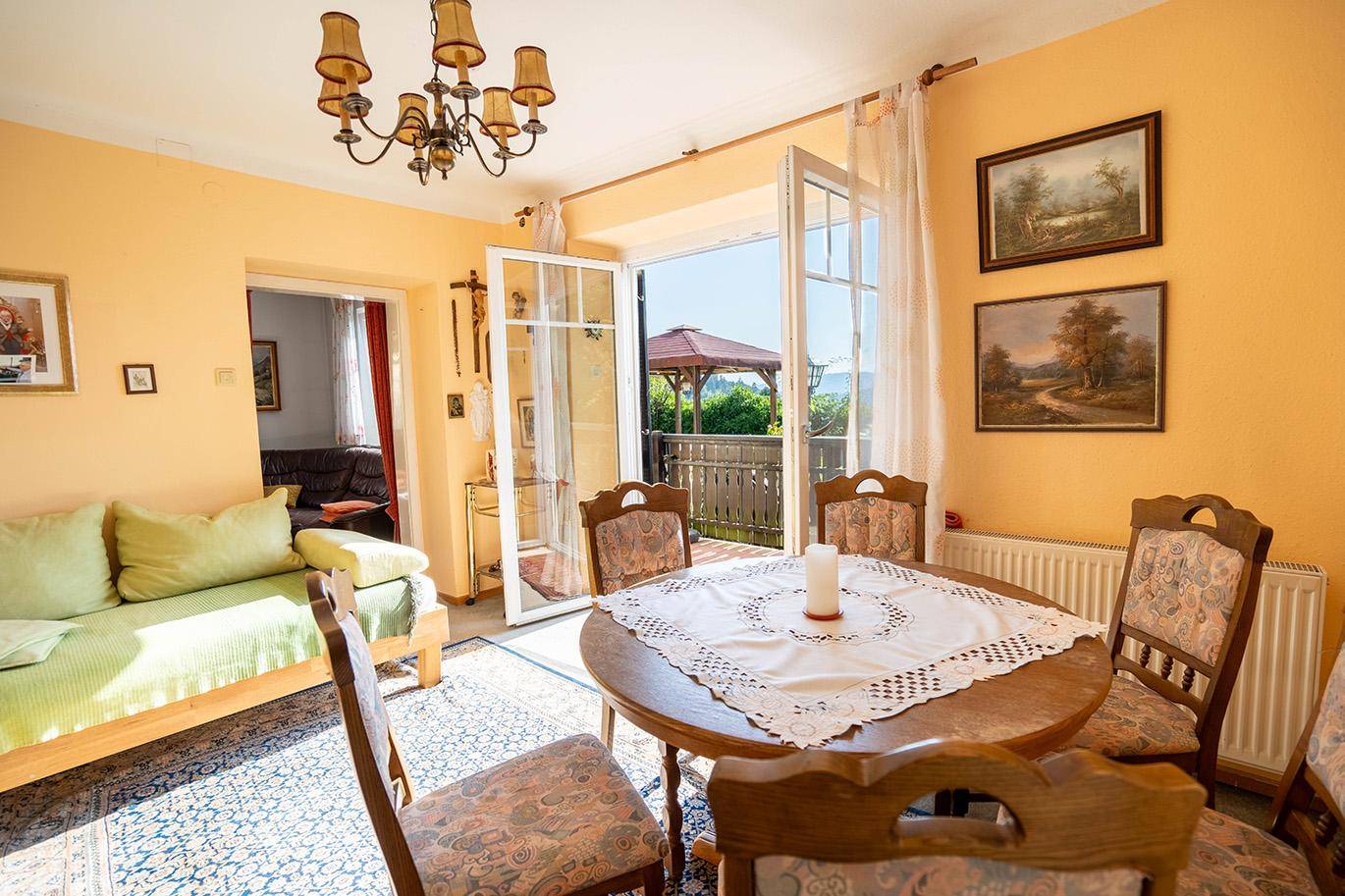 Gemütlicher Wohn- und Essbereich mit traditionellen Möbeln und direktem Zugang zum sonnigen Balkon.