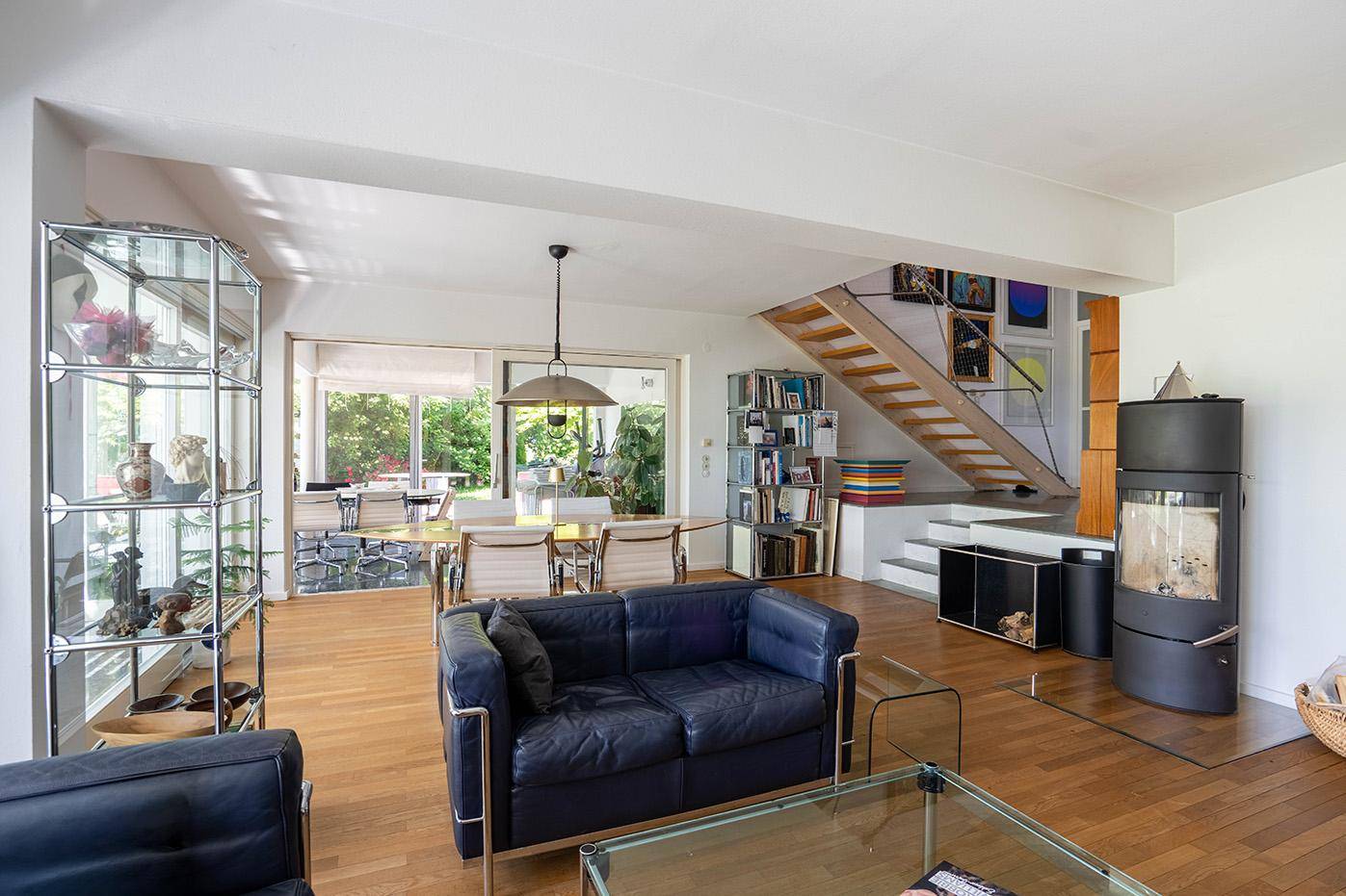 Geräumiges Wohnzimmer mit Holzboden, Kaminofen und Treppe, hell und modern eingerichtet.