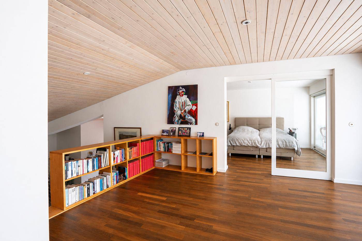 Schlafbereich mit Holzboden, Bücherregal und Zugang zum Schlafzimmer, mit Bergblick.