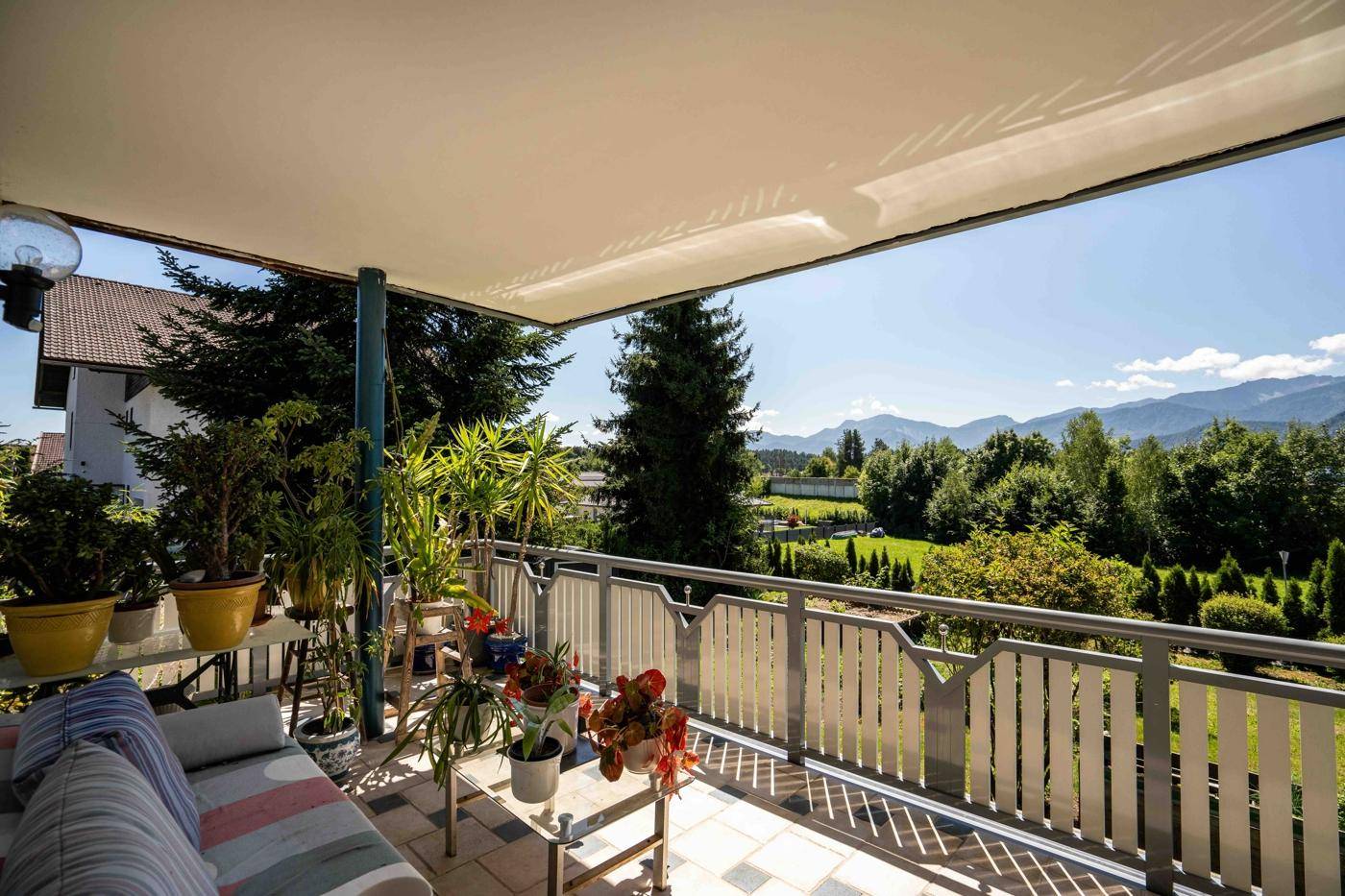 Geräumiger Balkon mit Sitzgelegenheiten, Pflanzen und weitem Blick auf die Berge.
