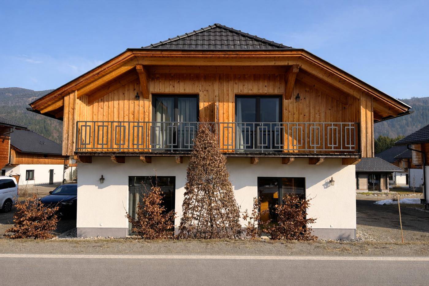 Frontansicht eines modernen Holzhauses mit Balkon und Satteldach.
