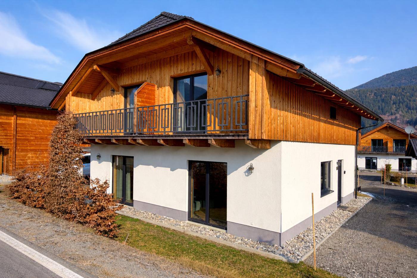 Seitenansicht des Holzhauses mit Balkon und Blick auf die umliegende Natur.