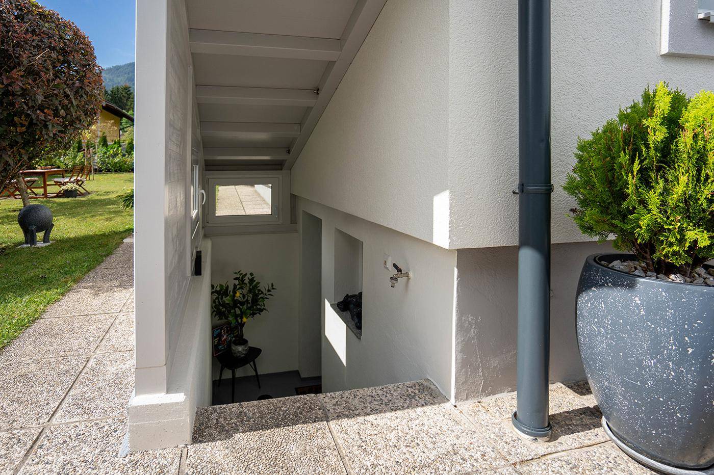 Außentreppe führt zum Untergeschoss mit kleinem Fenster und Zugang zum Gartenbereich.