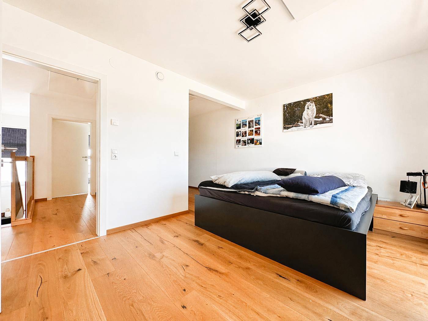Schlafzimmer mit Holzboden und großem Bett, das viel natürliches Licht erhält.
