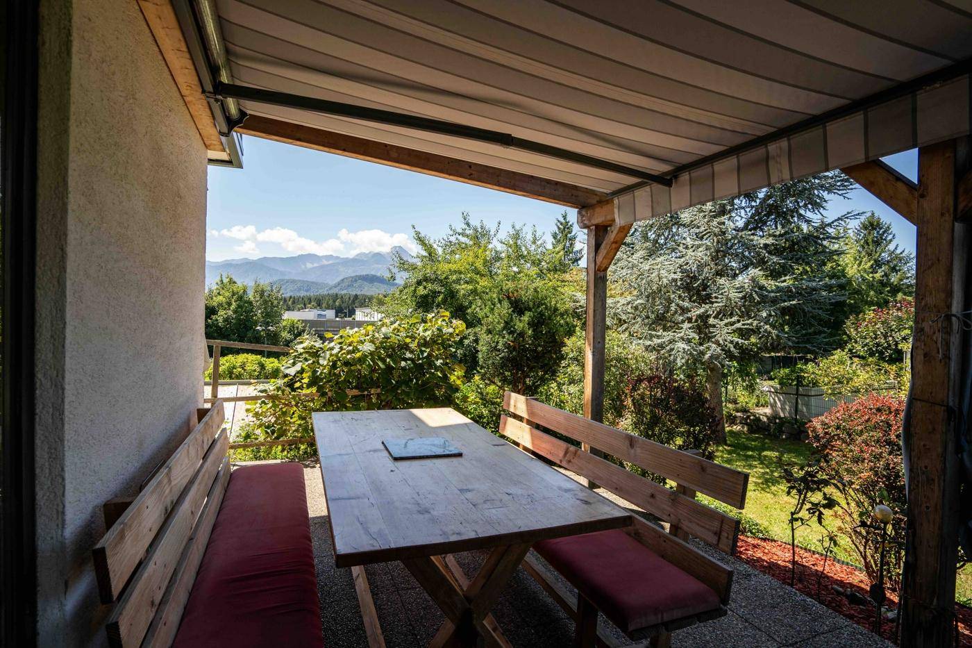 Gemütlicher überdachter Essbereich im Freien mit Holztisch und Bergblick.
