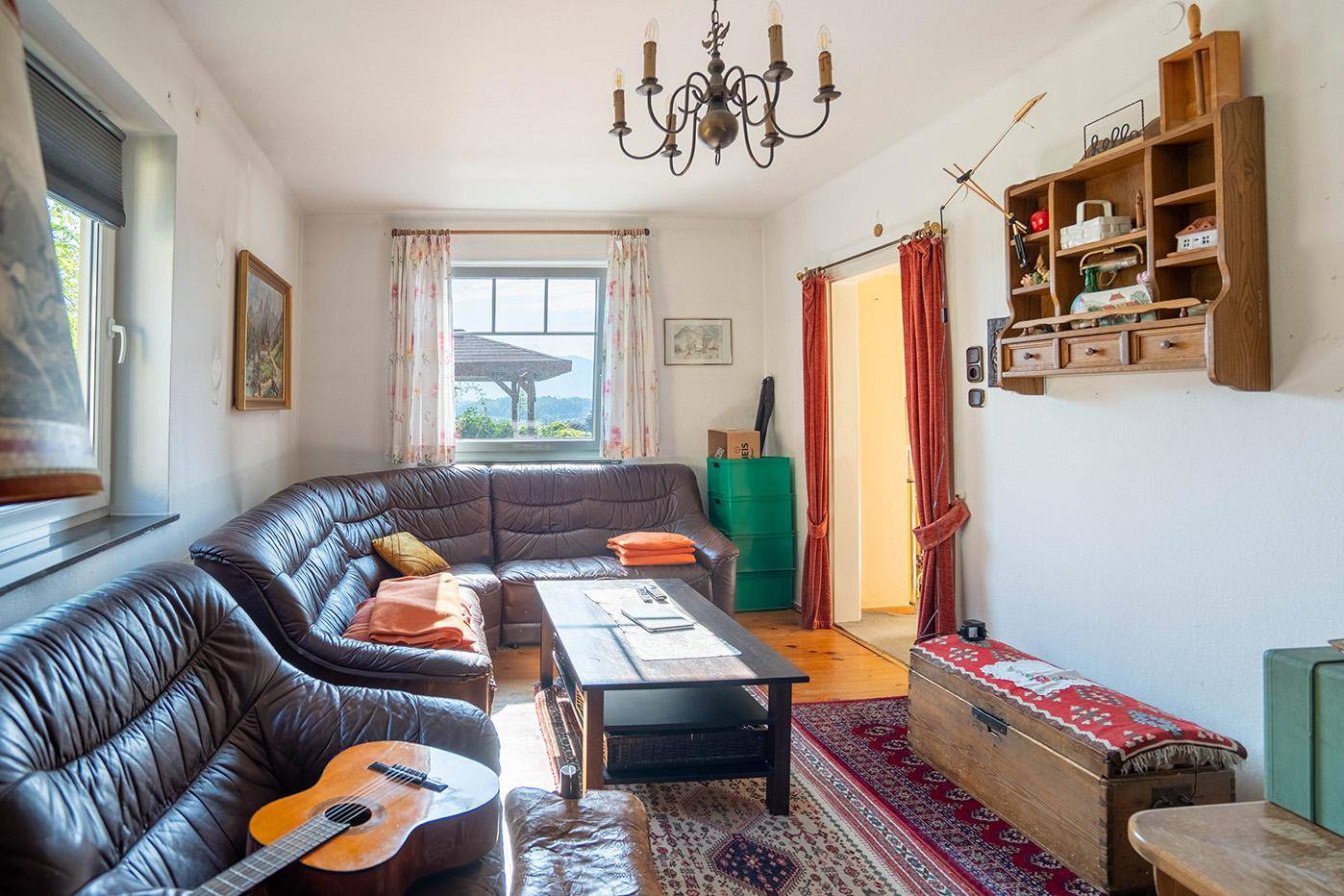 Rustikales Wohnzimmer mit bequemer Ledercouch, Holzboden und traditionellen Dekorationselementen.