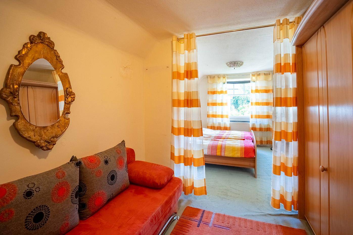 Geräumiges Schlafzimmer mit separatem Schlaf- und Wohnbereich, abgetrennt durch farbenfrohe Vorhänge.