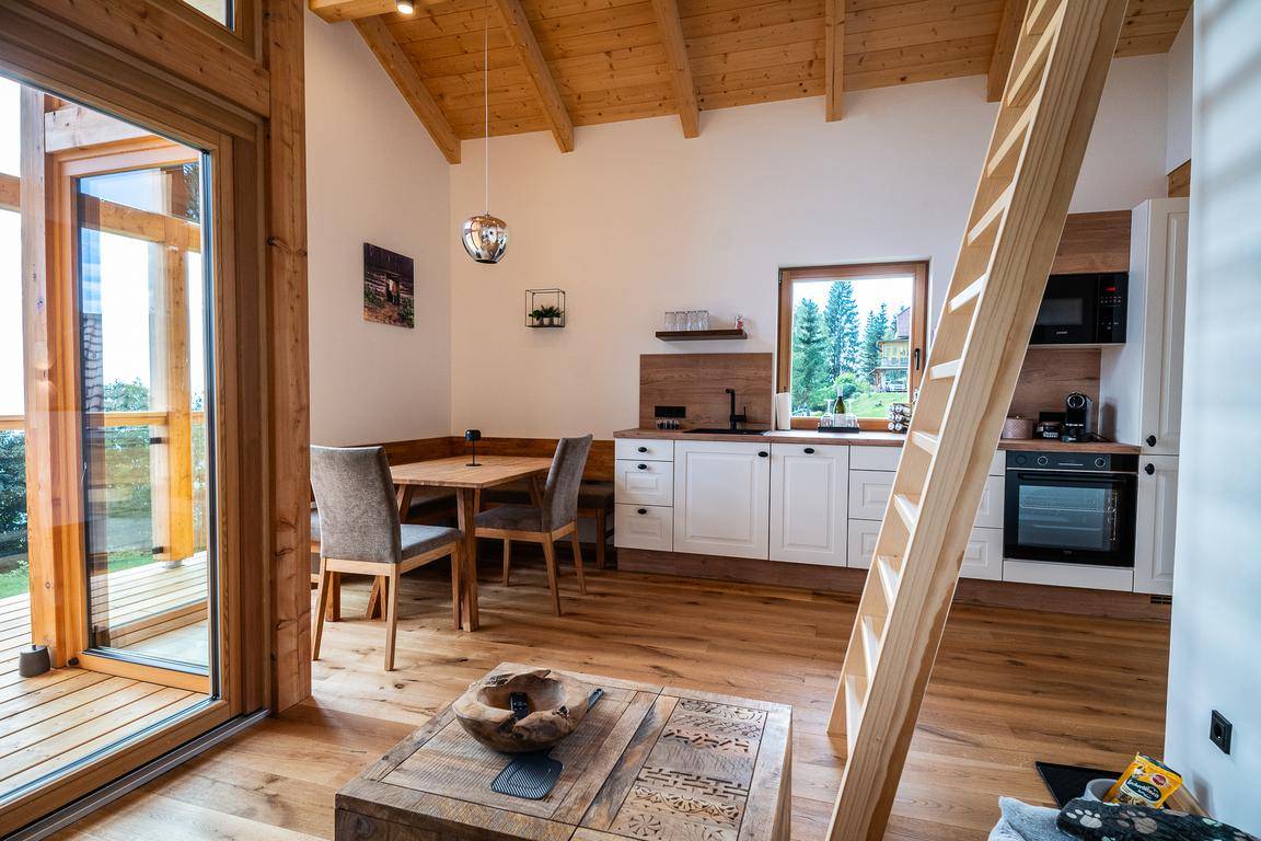 Moderne Küche mit Essbereich, Holzboden und Zugang zu einem Balkon oder einer Terrasse.