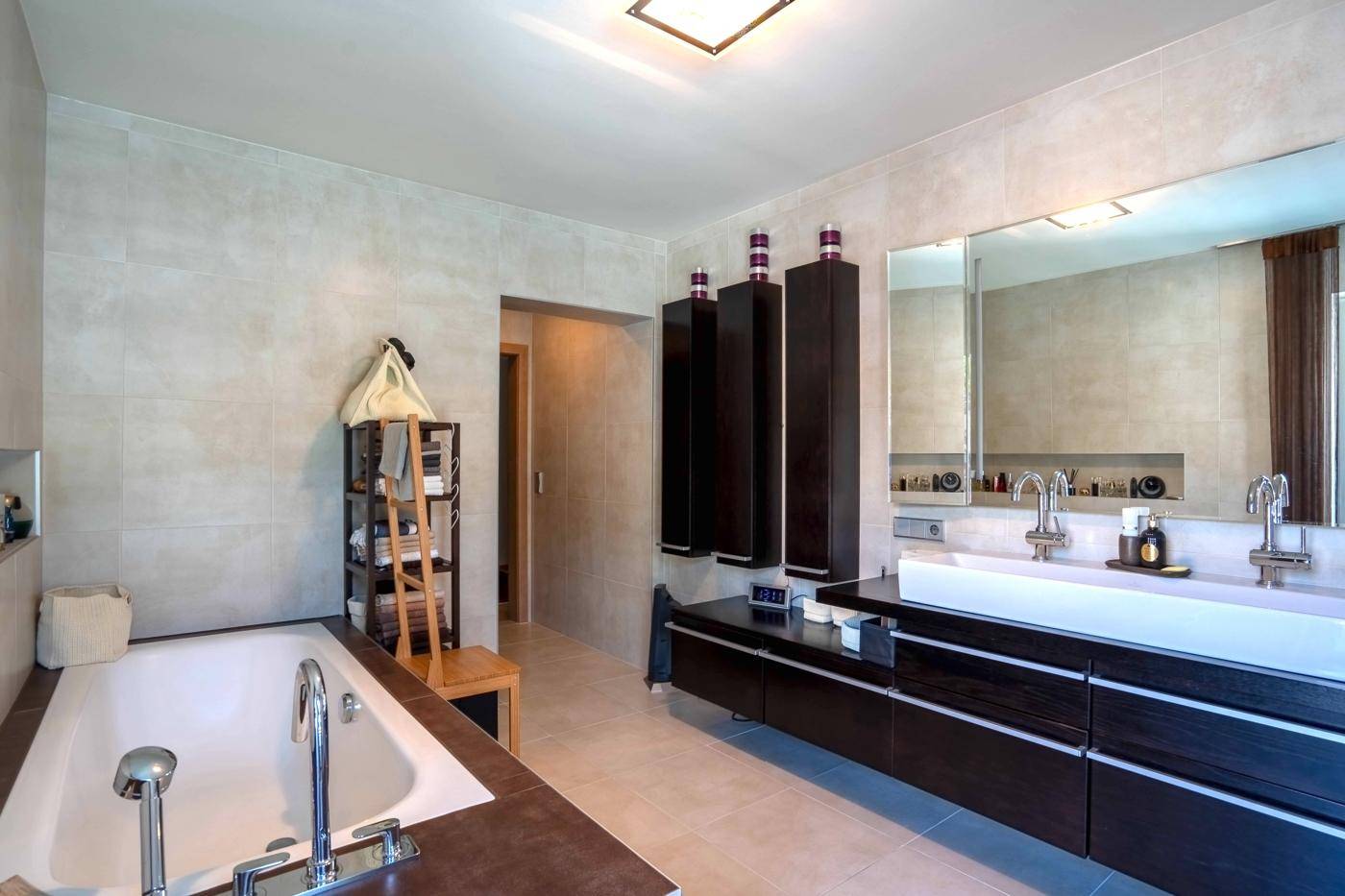 Modernes Badezimmer mit Doppelwaschbecken, Badewanne und dunklen Holzschränken.