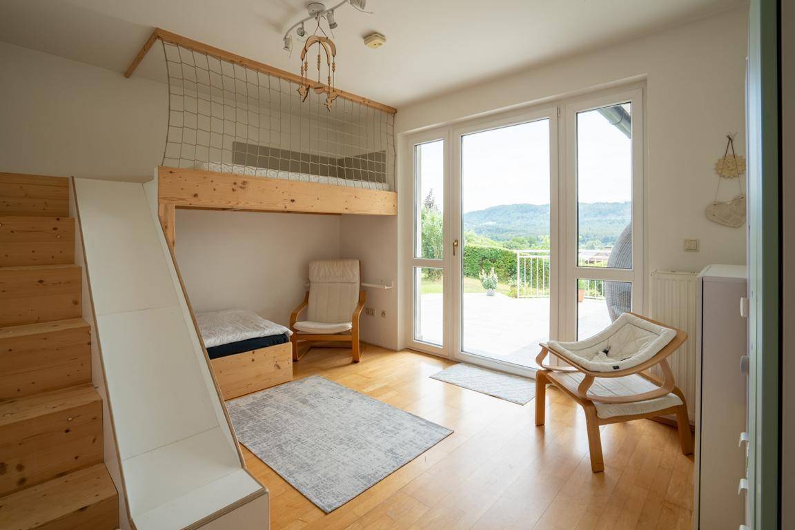Kinderzimmer mit Hochbett, Rutsche und Zugang zu einem Balkon mit Bergblick.