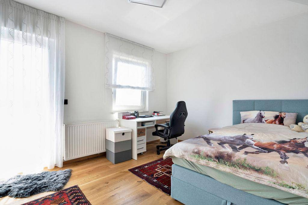 Kinderzimmer oder Arbeitszimmer mit Bett, Schreibtisch und hellem Holzboden.