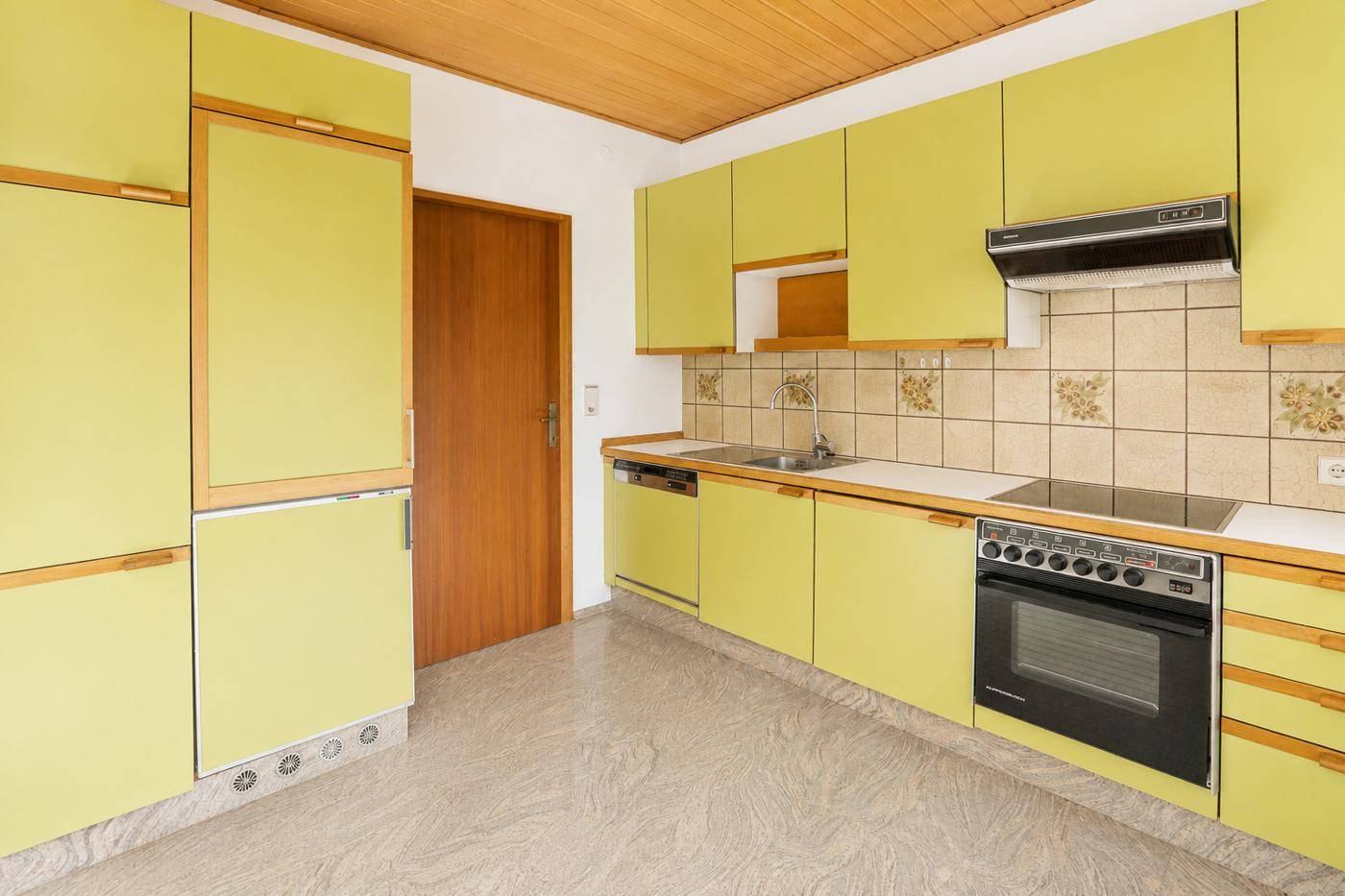 Helle Küche mit auffälligen lindgrünen Schränken, Fliesenboden und Holzdecke.