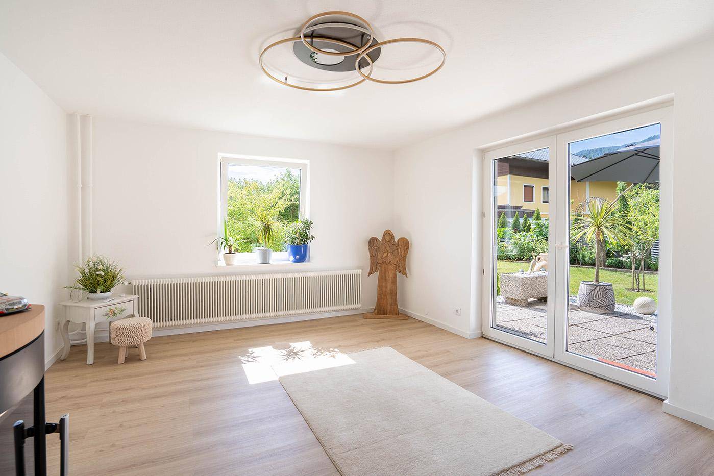 Lichtdurchfluteter Raum mit Laminatboden, großem Fenster und Zugang zur Terrasse und zum Garten.