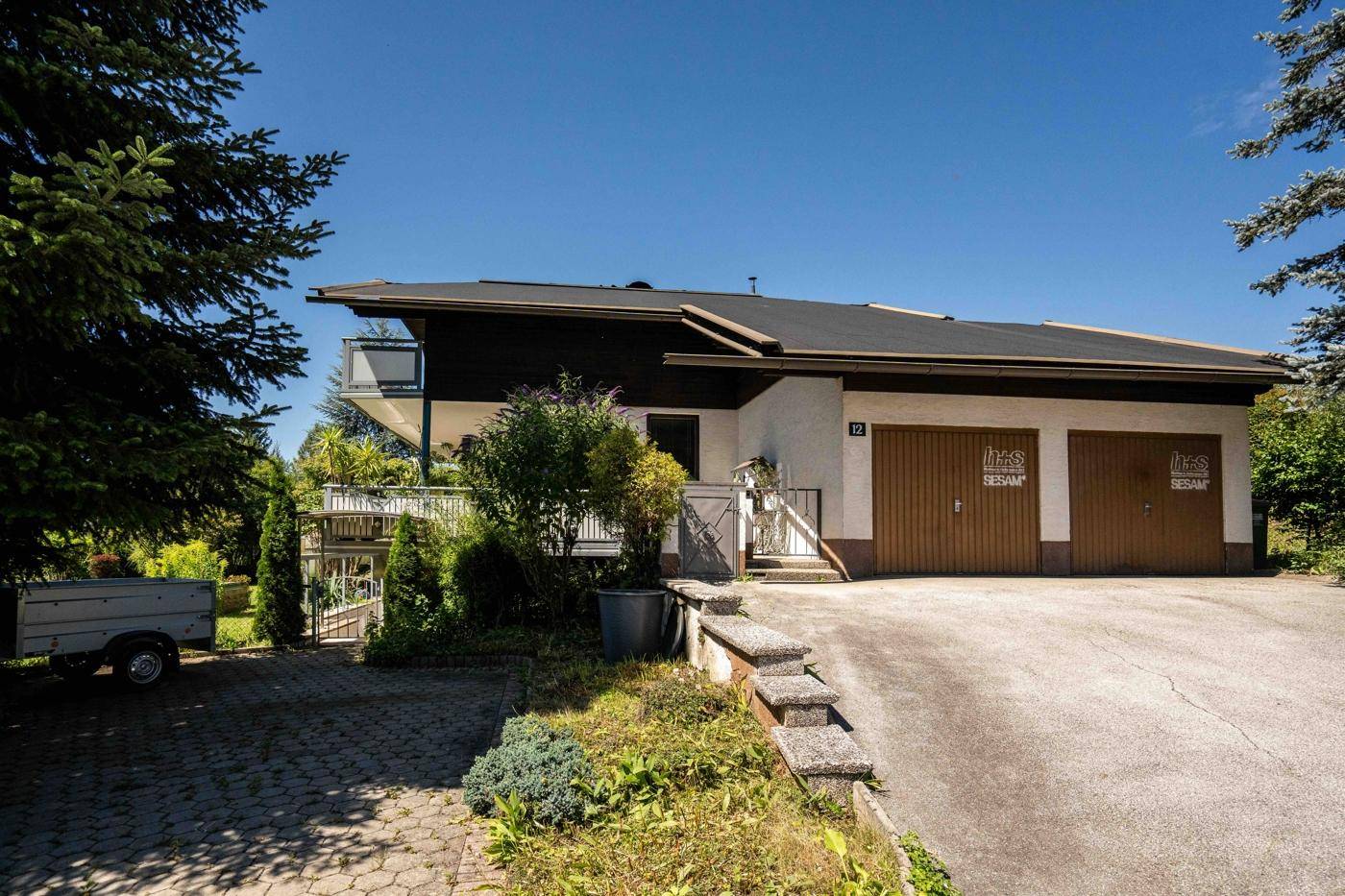 Vorderansicht des Hauses mit Doppelgarage, Auffahrt und gepflegter Grünfläche.