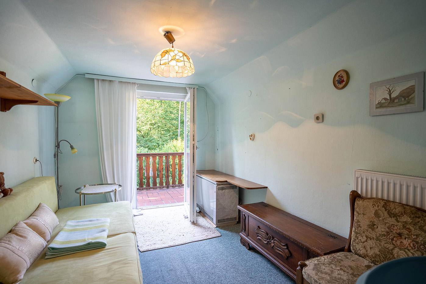 Helles Schlafzimmer mit Balkonzugang, einfacher Einrichtung und Blick ins Grüne.