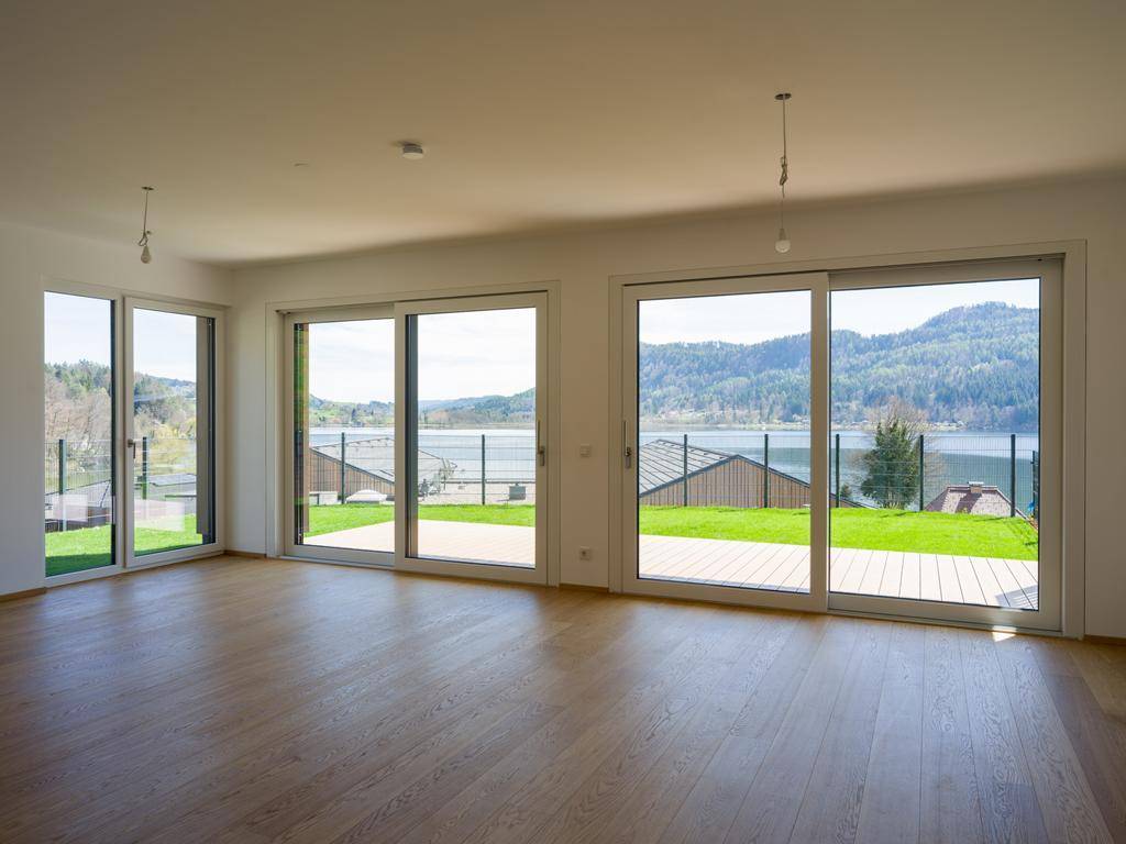 Heller Wohnraum mit Eichenparkett und großen Schiebetüren, die einen weiten Seeblick bieten.