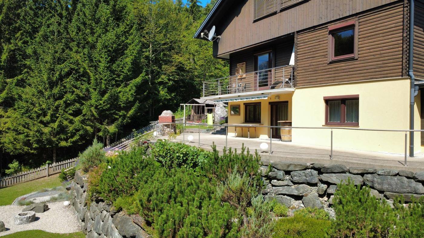 Terrasse am Haus mit Blick ins Grüne, umgeben von Felsen und mediterranen Pflanzen.
