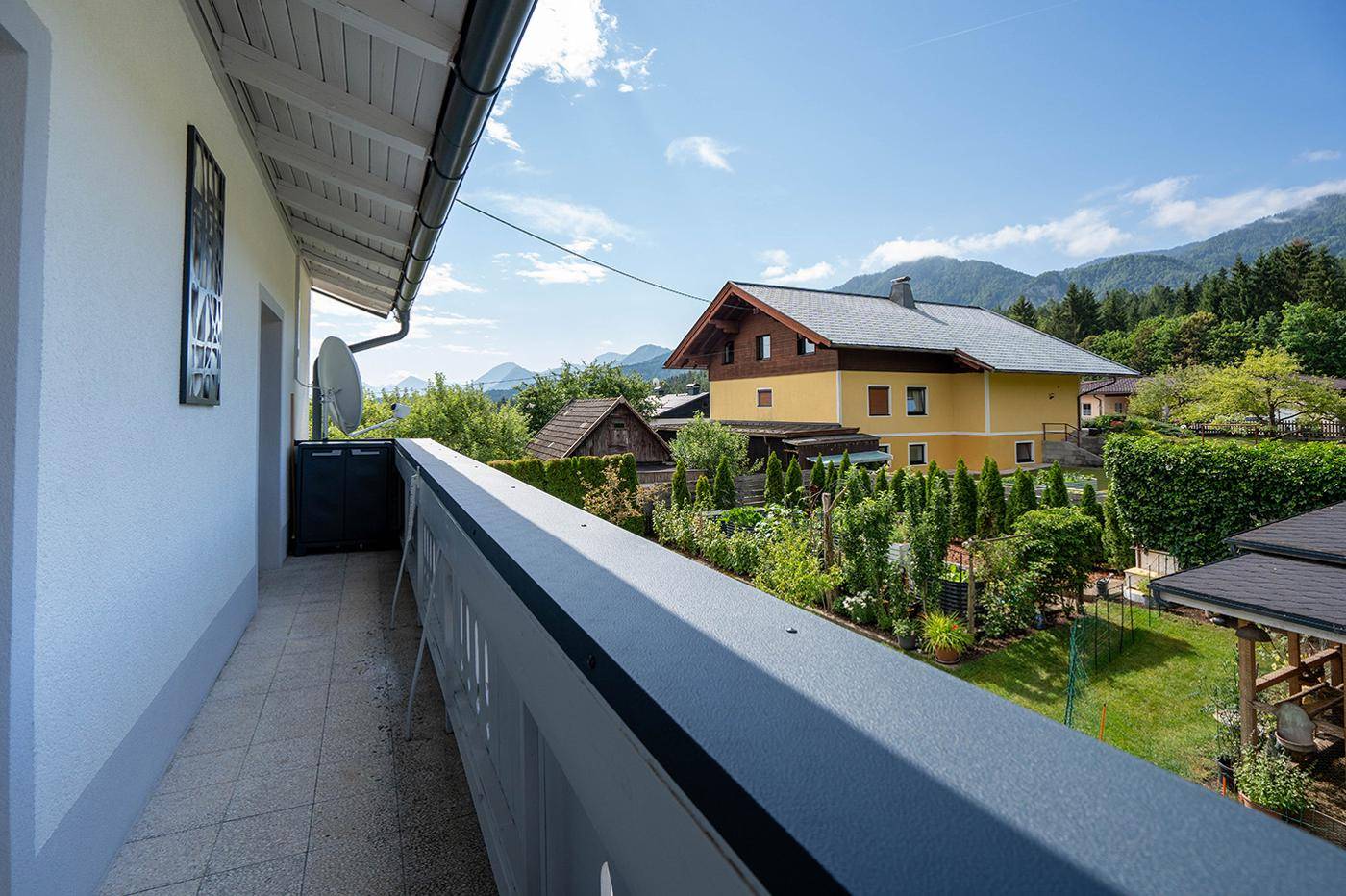 Balkon mit Fliesenboden und weitem Blick über die Nachbarschaft und die umliegenden Berge.