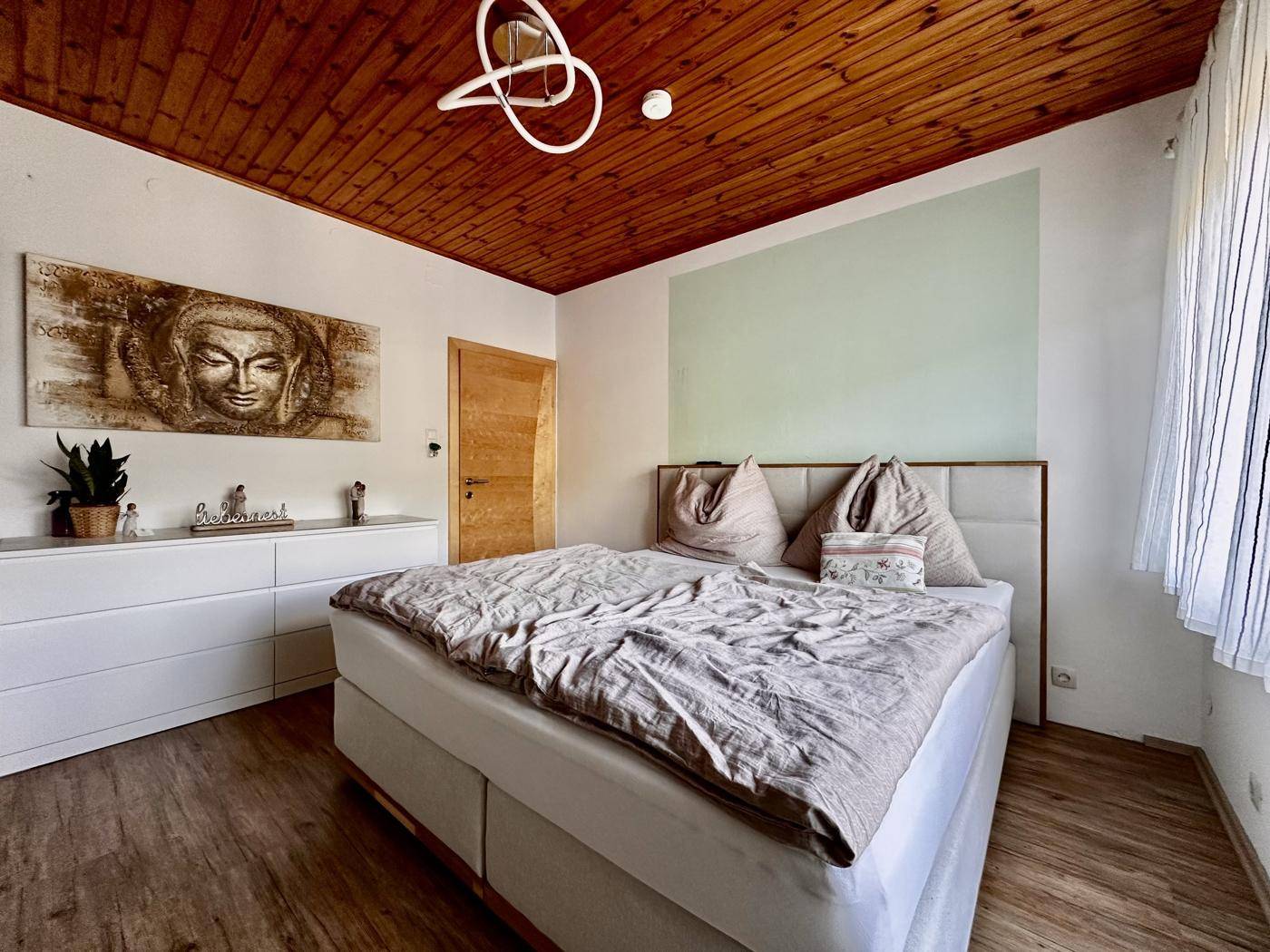 Helles Schlafzimmer mit Holzboden, Doppelbett und Holzdeckenverkleidung, modern dekoriert.