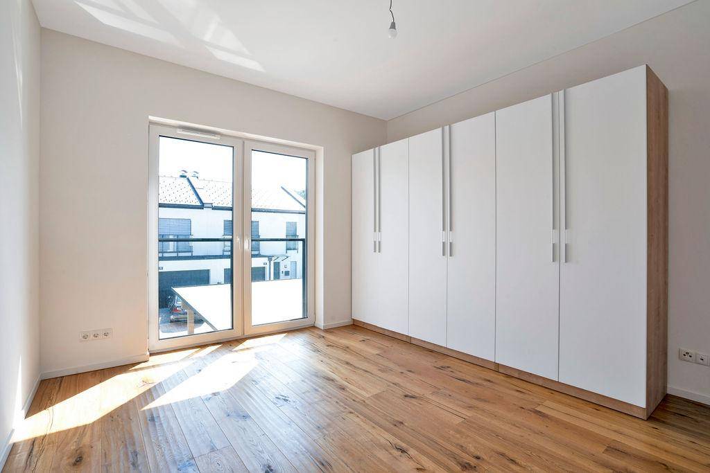 Schlafzimmer mit geräumigen weißen Kleiderschränken und einem großen Fenster, das den Raum erhellt.