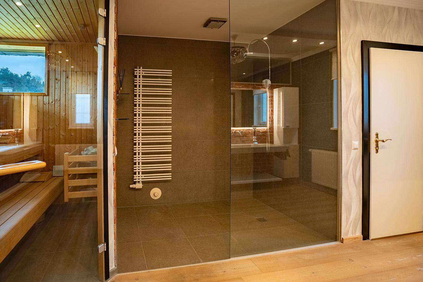 Modernes Badezimmer mit begehbarer Dusche, Sauna und beheiztem Handtuchhalter.