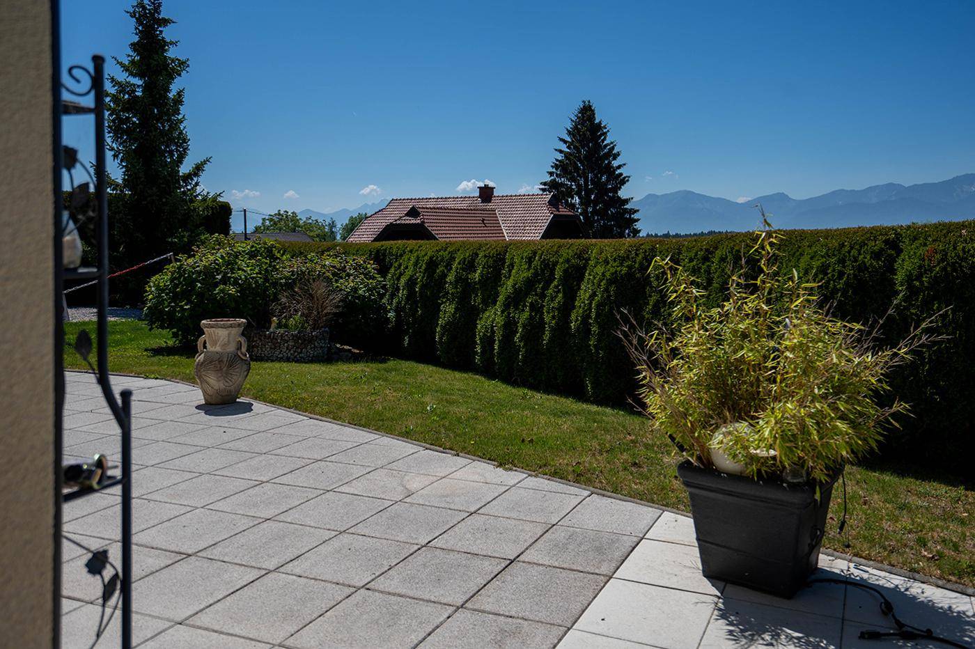 Gepflasterte Terrasse mit Pflanzen und weitem Blick auf die Berge und grüne Landschaft.