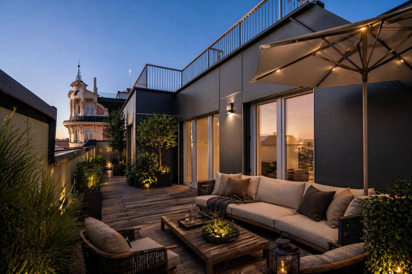 Elegante Dachterrasse mit bequemen Lounge-Möbeln und Blick auf die historische Architektur der Stadt bei Dämmerung.
