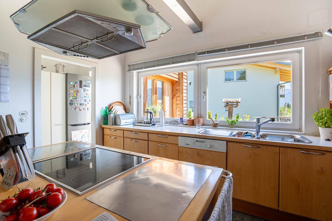 Detailansicht der Küche mit Induktionskochfeld, Spüle und Blick nach draußen.
