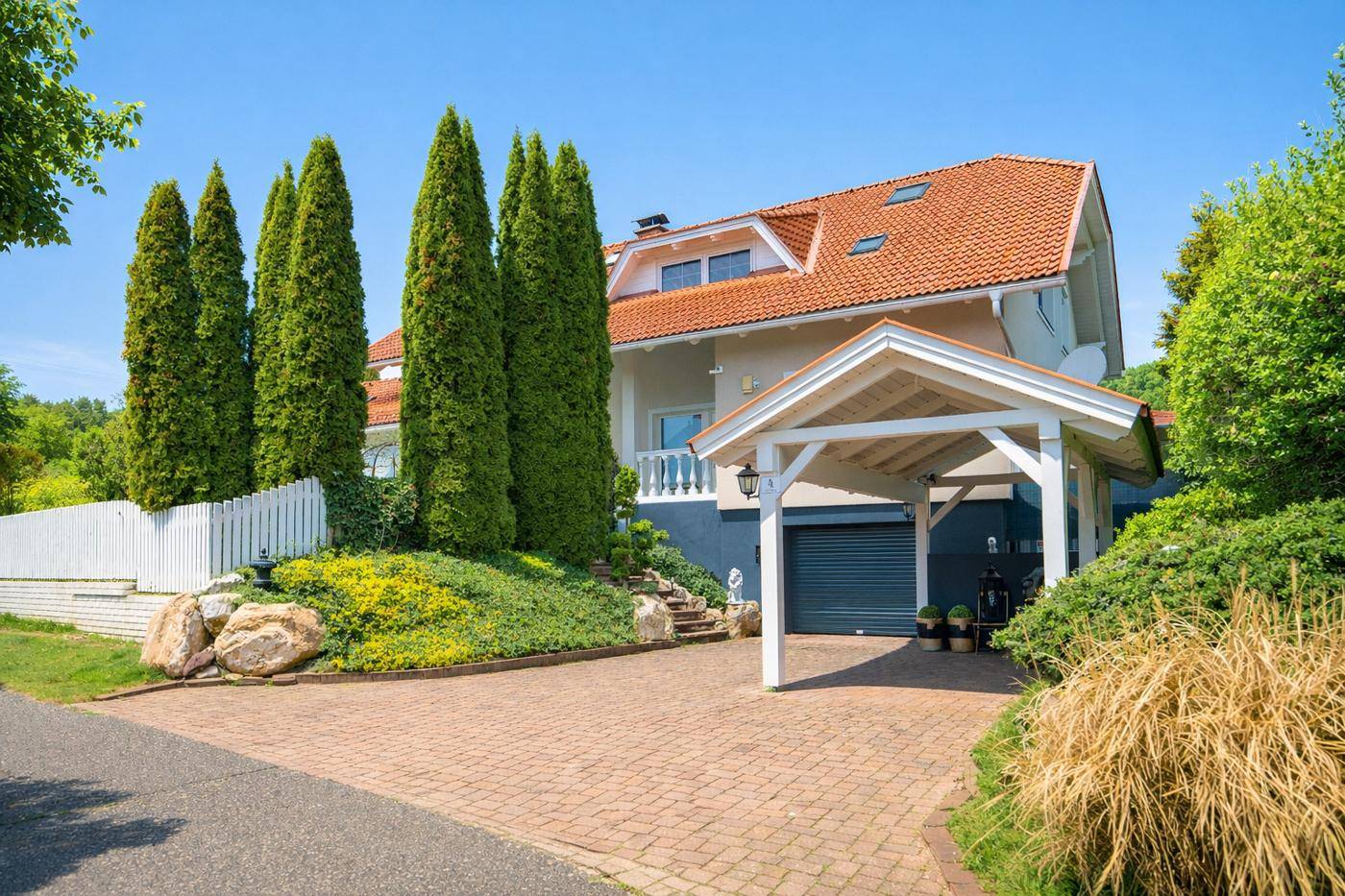 Elegantes Einfamilienhaus mit Carport, gepflasterter Auffahrt und gepflegtem Vorgarten.