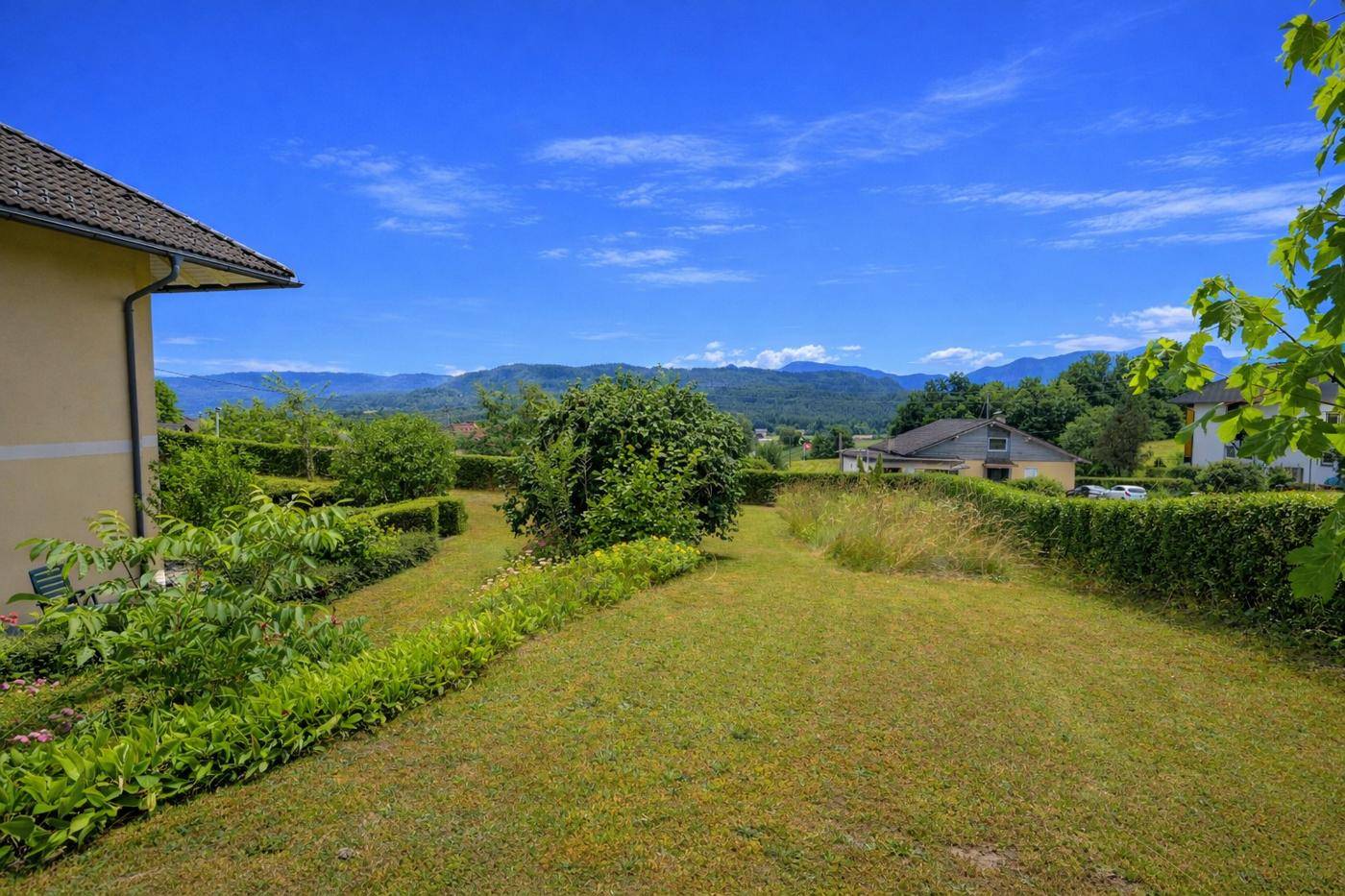 Großer Garten mit weitem Blick über die grüne Landschaft und die umliegenden Berge.