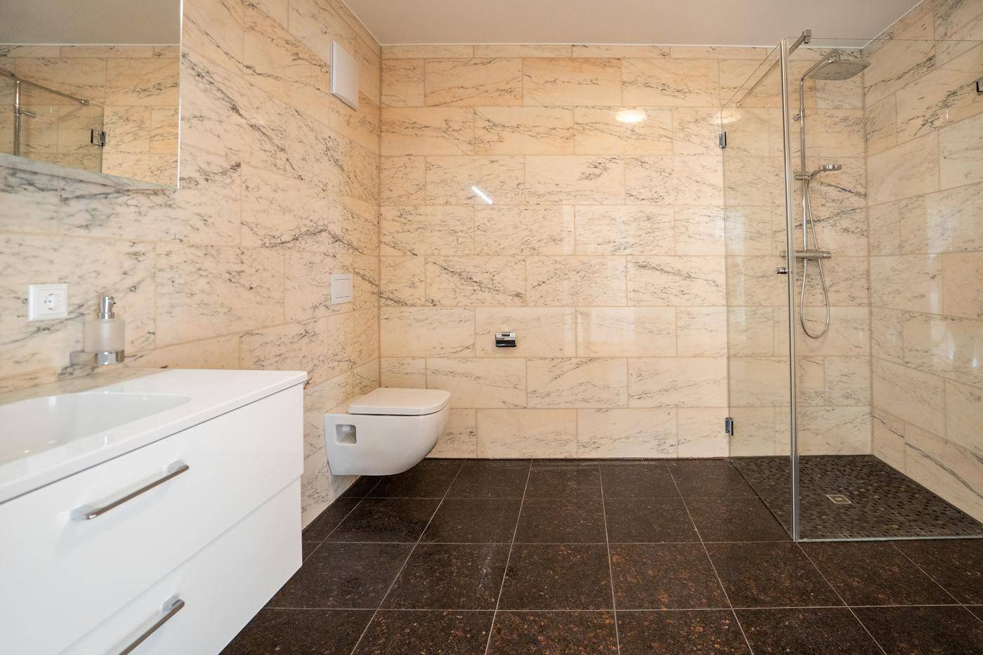 Modernes Badezimmer mit beigefarbenen Marmorfliesen, begehbarer Dusche und Wand-WC.